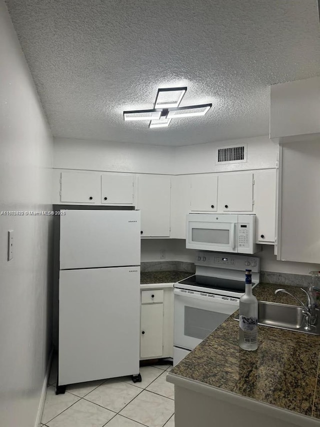 212 Lake Pointe Dr Unit 210, Oakland Park, FL 33309 - kitchen featuring white appliances, dark countertops, a textured ceiling, white cabinets, and light tile patterned floors