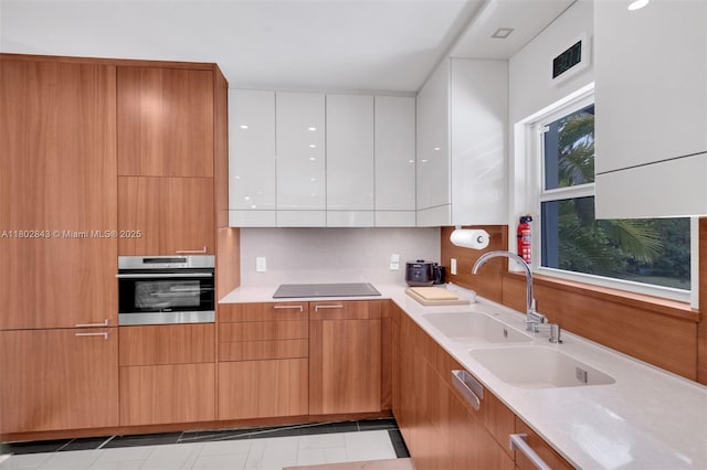 726 NE 17th Way, Fort Lauderdale, FL 33304 - kitchen with stainless steel oven, modern cabinets, light countertops, black electric stovetop, and white cabinets