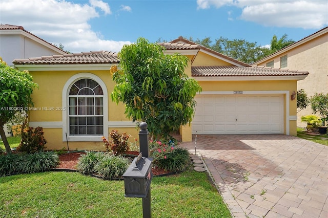 mediterranean / spanish-style home featuring stucco siding, a tile roof, decorative driveway, and a garage