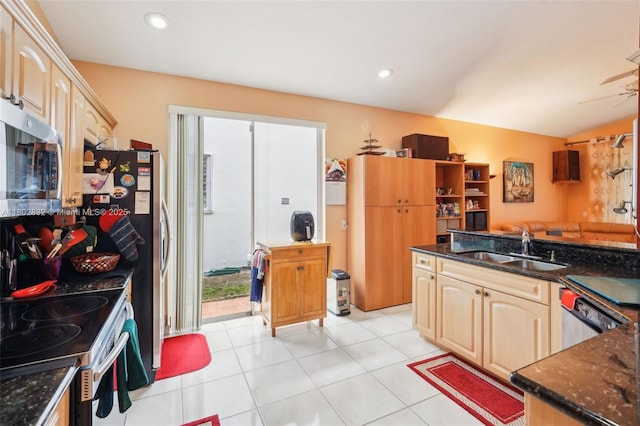 kitchen with stainless steel appliances, a sink, dark stone counters, open floor plan, and recessed lighting