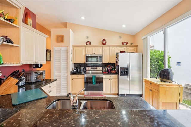 kitchen featuring appliances with stainless steel finishes, a sink, open shelves, dark stone counters, and lofted ceiling
