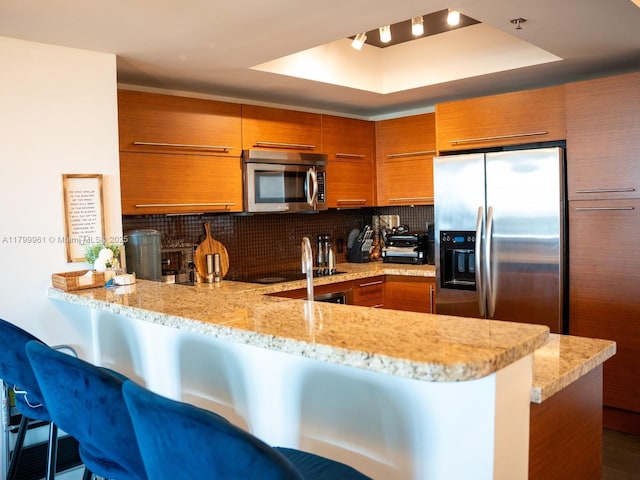 2681 N Flamingo Rd Unit 1206S, Sunrise, FL 33323 - kitchen with appliances with stainless steel finishes, brown cabinets, a raised ceiling, and decorative backsplash