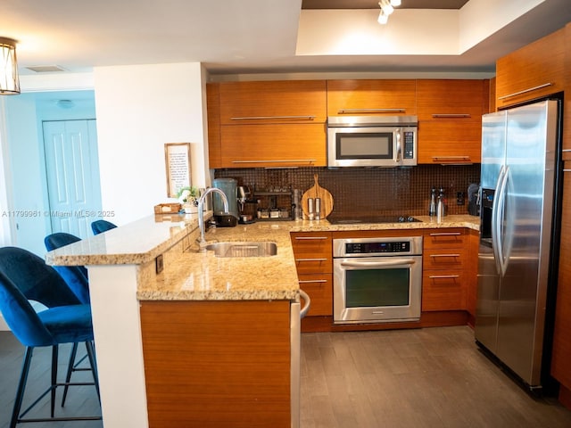 2681 N Flamingo Rd Unit 1206S, Sunrise, FL 33323 - kitchen with appliances with stainless steel finishes, brown cabinets, a sink, a peninsula, and a kitchen bar
