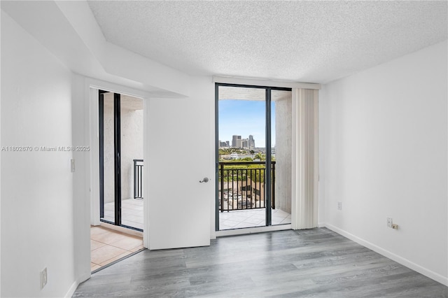 540 Brickell Key Dr Unit 904, Miami, FL 33131 - empty room featuring a textured ceiling, wood finished floors, a wall of windows, and baseboards
