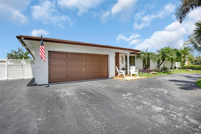 6001 SW 18th St, Plantation, FL 33317 - view of front facade featuring stucco siding, an attached garage, asphalt driveway, and fence
