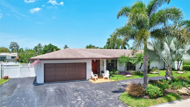 6001 SW 18th St, Plantation, FL 33317 - ranch-style house with an attached garage, asphalt driveway, stucco siding, and fence