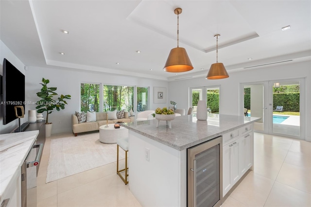 1415 Madrid St, Coral Gables, FL 33134 - kitchen with wine cooler, a tray ceiling, white cabinets, light tile patterned floors, and a breakfast bar