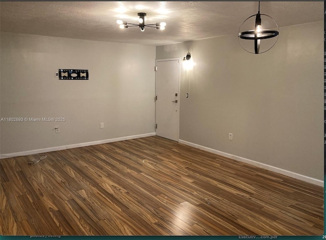 16518 NE 26th Ave Unit 305, North Miami Beach, FL 33160 - unfurnished room with a chandelier, dark wood-style floors, baseboards, and a textured ceiling