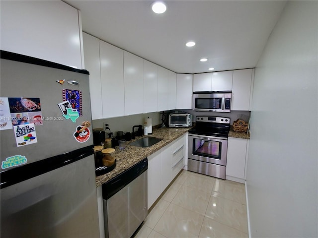 16518 NE 26th Ave Unit 305, North Miami Beach, FL 33160 - kitchen featuring appliances with stainless steel finishes, a sink, white cabinets, stone countertops, and light tile patterned flooring