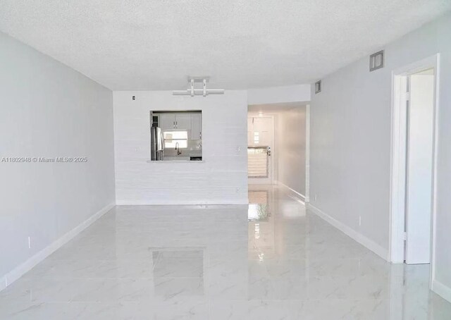 691 S Hollybrook Dr Unit 208, Pembroke Pines, FL 33025 - spare room featuring baseboards, light marble finish flooring, a textured ceiling, and a sink