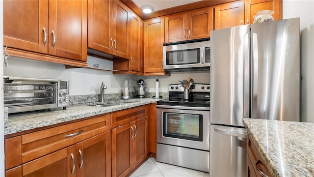 1012 Berkshire A 1012, Deerfield Beach, FL 33442 - kitchen featuring stainless steel appliances, a sink, brown cabinetry, light stone counters, and light tile patterned floors