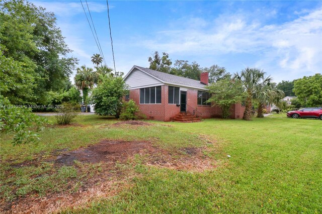 2196 Traymore Rd, Jacksonville, FL 32207 - view of side of property with brick siding, a chimney, and a yard