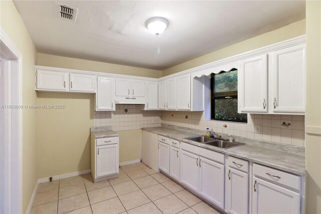 2196 Traymore Rd, Jacksonville, FL 32207 - kitchen with a sink, under cabinet range hood, light tile patterned floors, white cabinetry, and decorative backsplash