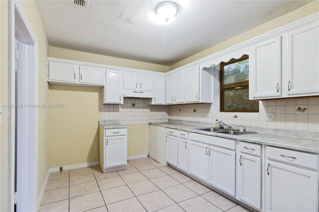 2196 Traymore Rd, Jacksonville, FL 32207 - kitchen featuring a sink, under cabinet range hood, light tile patterned floors, white cabinets, and decorative backsplash