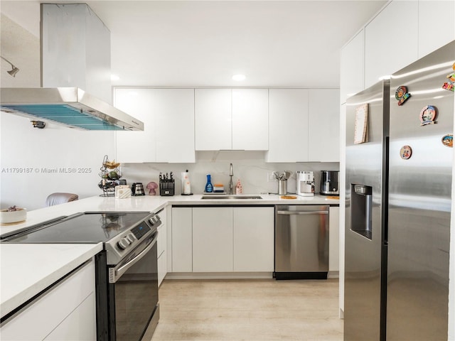 kitchen featuring appliances with stainless steel finishes, island exhaust hood, a sink, light countertops, and white cabinetry