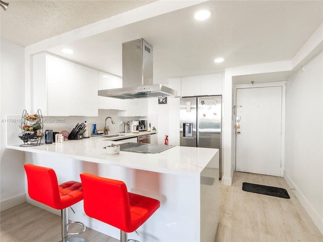 kitchen featuring island range hood, light wood-style floors, a peninsula, recessed lighting, and light countertops
