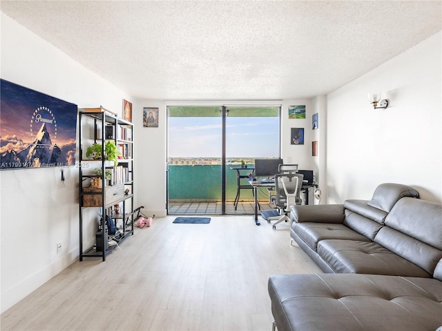 living room featuring an office area, a textured ceiling, wood finished floors, floor to ceiling windows, and baseboards