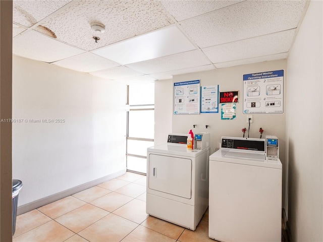 community laundry featuring washing machine and clothes dryer, light tile patterned floors, and baseboards