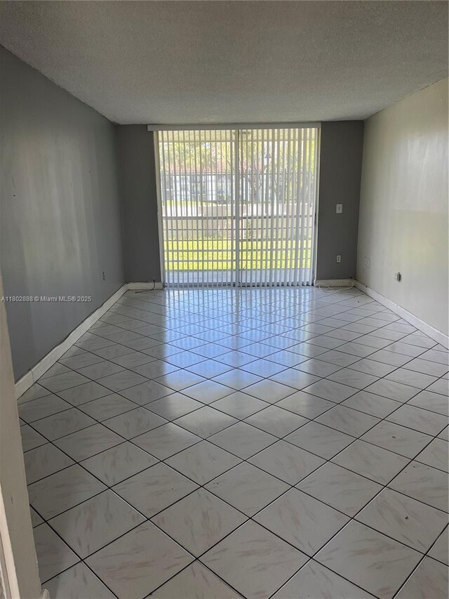 14155 SW 87th St Unit E110, Miami, FL 33183 - spare room with a textured ceiling, light tile patterned flooring, and baseboards