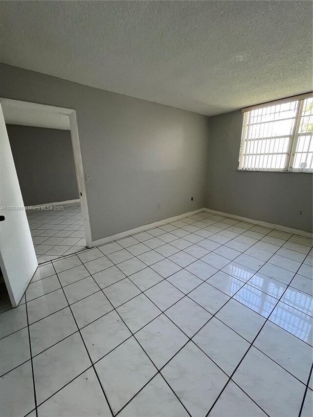 14155 SW 87th St Unit E110, Miami, FL 33183 - spare room with light tile patterned floors, a textured ceiling, and baseboards
