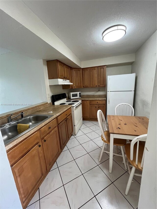 14155 SW 87th St Unit E110, Miami, FL 33183 - kitchen featuring white appliances, under cabinet range hood, a sink, brown cabinetry, and a textured ceiling