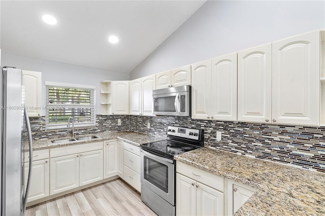 kitchen featuring a sink, stainless steel appliances, lofted ceiling, light stone countertops, and tasteful backsplash