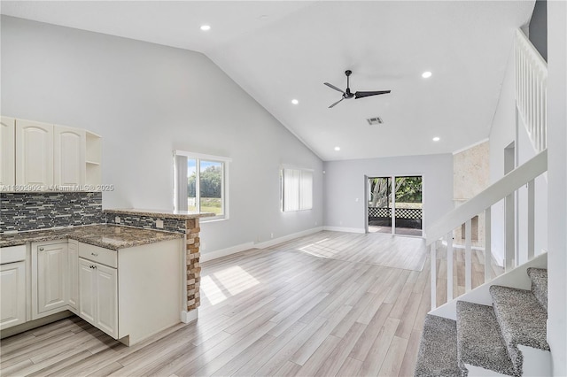 kitchen with high vaulted ceiling, a ceiling fan, open floor plan, backsplash, and baseboards