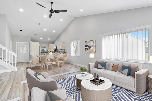 living room featuring ceiling fan, high vaulted ceiling, stairway, baseboards, and recessed lighting