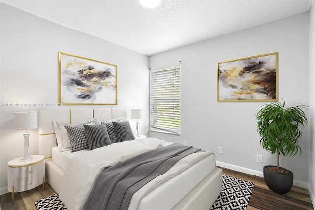 bedroom featuring wood finished floors, baseboards, and a textured ceiling