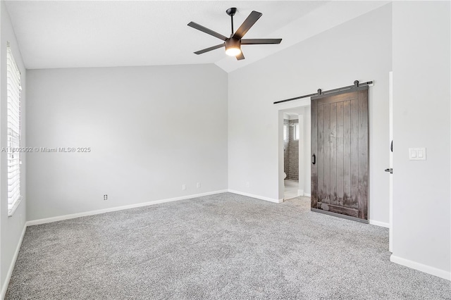 empty room with carpet, ceiling fan, a barn door, baseboards, and high vaulted ceiling