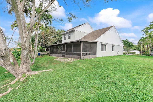 rear view of house with a sunroom, a lawn, and stucco siding