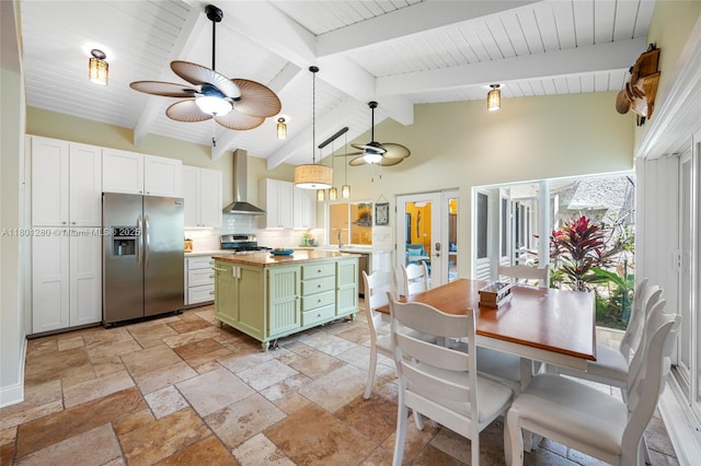 kitchen with appliances with stainless steel finishes, green cabinetry, wall chimney range hood, a ceiling fan, and decorative backsplash