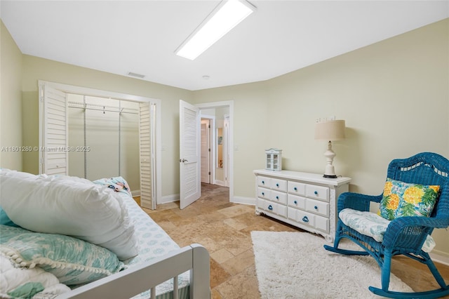 bedroom with baseboards, a closet, and light stone finish floors
