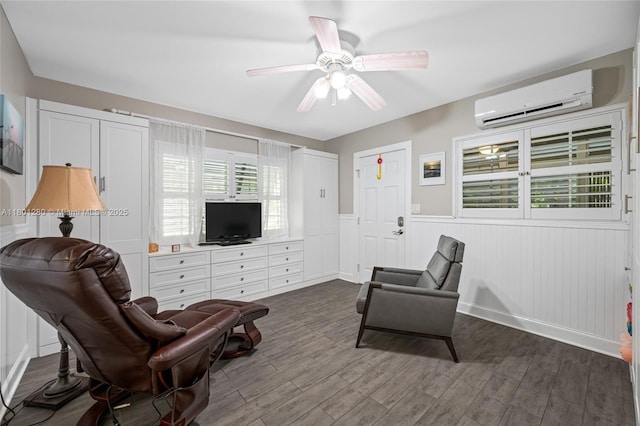 sitting room with a wall mounted AC, wainscoting, dark wood-style floors, and plenty of natural light
