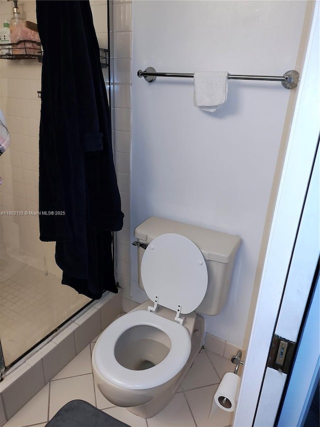 bathroom with a shower stall, toilet, and tile patterned flooring