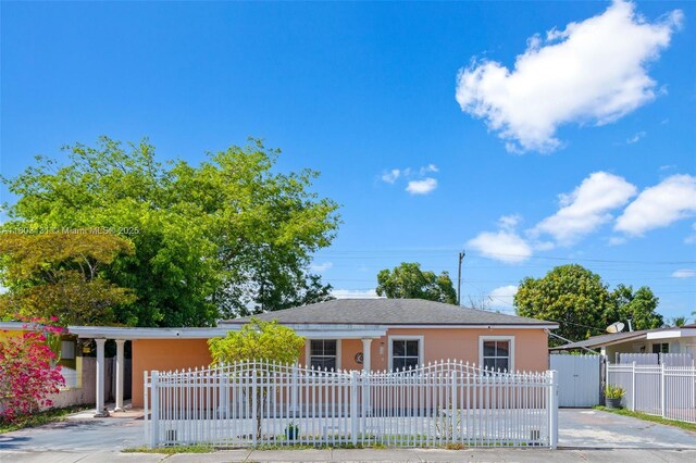 911 E 32nd St, Hialeah, FL 33013 - view of front facade with a fenced front yard, a carport, a gate, stucco siding, and driveway