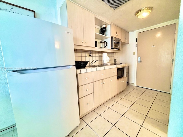 19201 Collins Ave Unit 606, Sunny Isles Beach, FL 33160 - kitchen featuring freestanding refrigerator, tile countertops, open shelves, decorative backsplash, and light tile patterned flooring