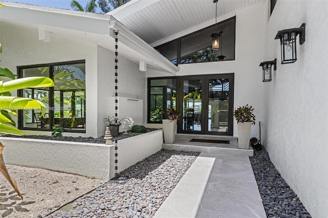 view of exterior entry featuring french doors and stucco siding