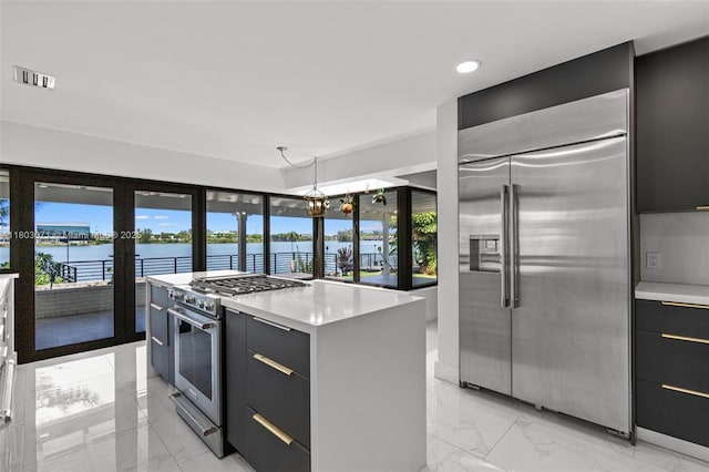 kitchen featuring high end appliances, modern cabinets, light marble finish flooring, and recessed lighting