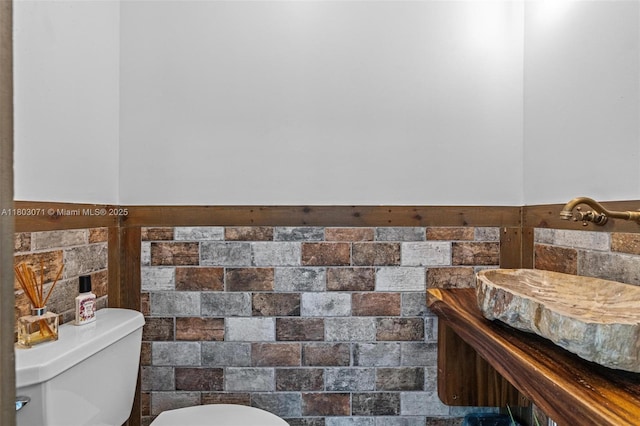 half bath with toilet and tile walls