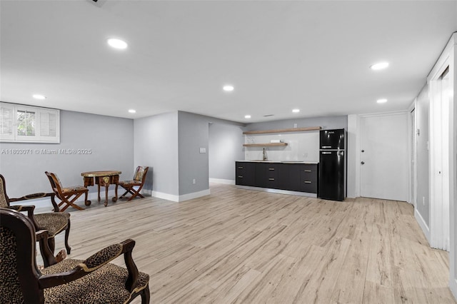 living area featuring bar with sink, baseboards, light wood-style floors, and recessed lighting