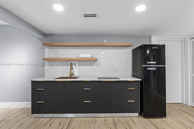 kitchen with freestanding refrigerator, a sink, modern cabinets, and dark cabinets