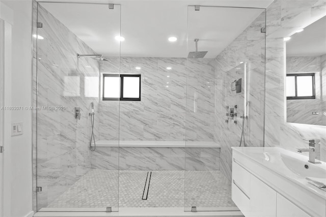 full bathroom with a marble finish shower and vanity