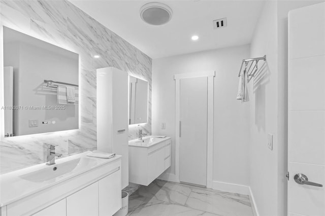 bathroom featuring marble finish flooring, two vanities, baseboards, and recessed lighting