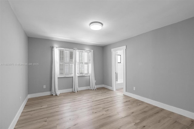 unfurnished room with light wood-type flooring and baseboards