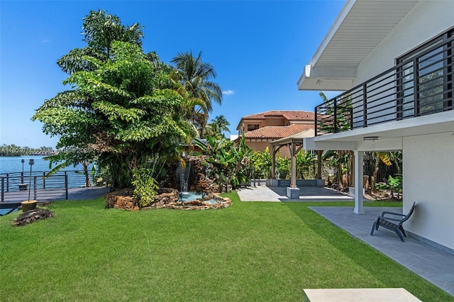 view of yard featuring a patio area, a water view, and a balcony