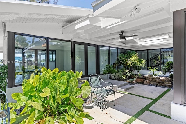 sunroom with ceiling fan and beam ceiling