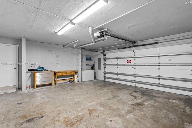 garage with a garage door opener, a workshop area, and electric panel