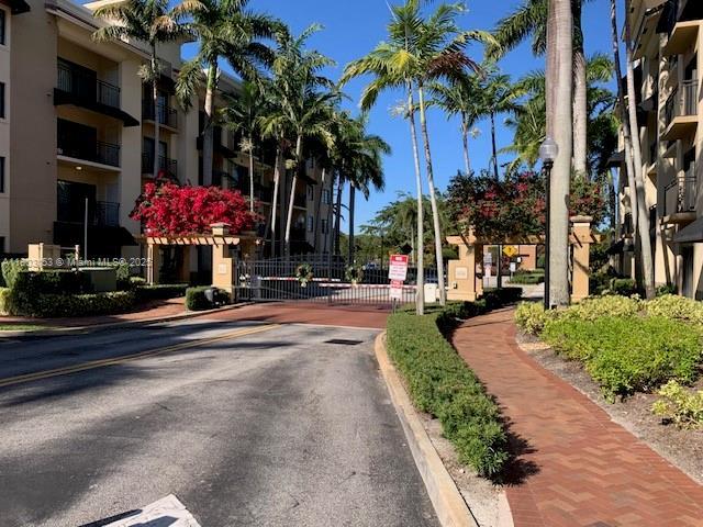 4907 Midtown Ln Unit 1113, Palm Beach Gardens, FL 33418 - view of asphalt street with curbs, a gate, sidewalks, and a gated entry