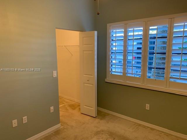 4907 Midtown Ln Unit 1113, Palm Beach Gardens, FL 33418 - unfurnished bedroom featuring light colored carpet, baseboards, a closet, and a walk in closet